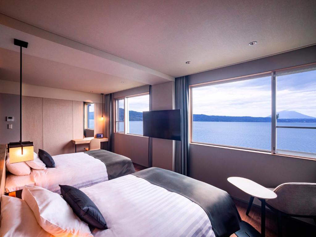 une chambre d'hôtel avec deux lits et une grande fenêtre dans l'établissement The Lake View Toya Nonokaze Resort, à Lac Tōya