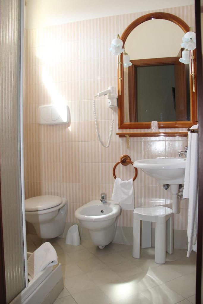 une salle de bain avec un lavabo, des toilettes et un miroir dans l'établissement Hotel Geranio Rosso, à Stintino 59 autres photos
