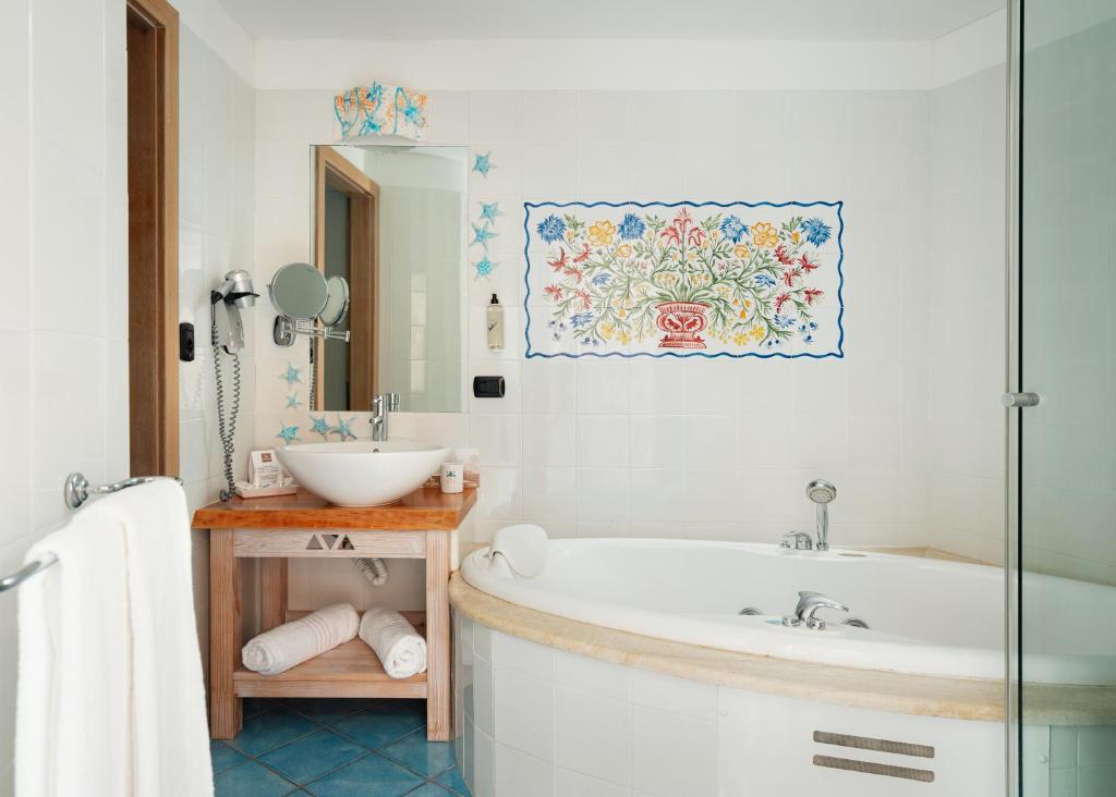 une salle de bain avec une baignoire et un lavabo dans l'établissement Hotel Resort & Spa Baia Caddinas, à Golfo Aranci