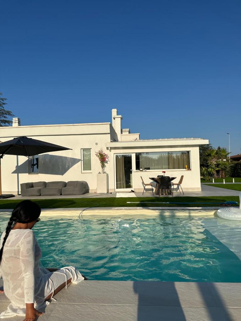 - une petite fille assise à côté d'une piscine dans l'établissement Villa Ikal, à Modugno