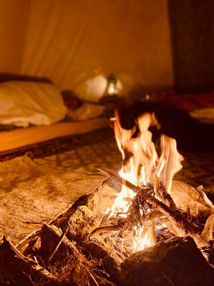 un feu brûle dans une pièce avec un lit dans l'établissement Terra-Tipike, Tipi à la ferme entre Terre et Mer, à Trébry