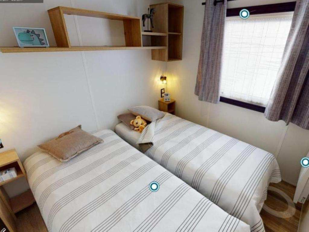 deux lits dans une petite pièce avec une fenêtre dans l'établissement MH 541 Spacieux 40m2 avec 2 chambres 1 salle de bain dans Camping 4 étoiles, à Saint-Julien-en-Born 7 autres photos