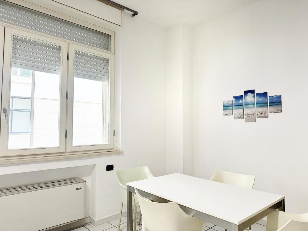 une salle à manger blanche avec une table et des chaises blanches dans l'établissement Mediterranea Residence, à Salerne