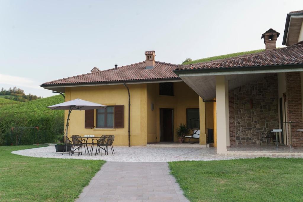 Cette maison dispose d'une terrasse avec des tables et un parasol. dans l'établissement Ca du Ji'uu, villa con piscina, à Castellinaldo