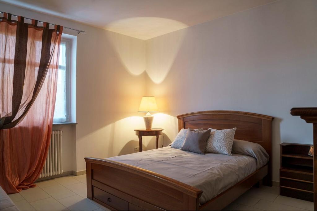 une chambre avec un lit avec une lampe et une fenêtre dans l'établissement Ca du Ji'uu, villa con piscina, à Castellinaldo