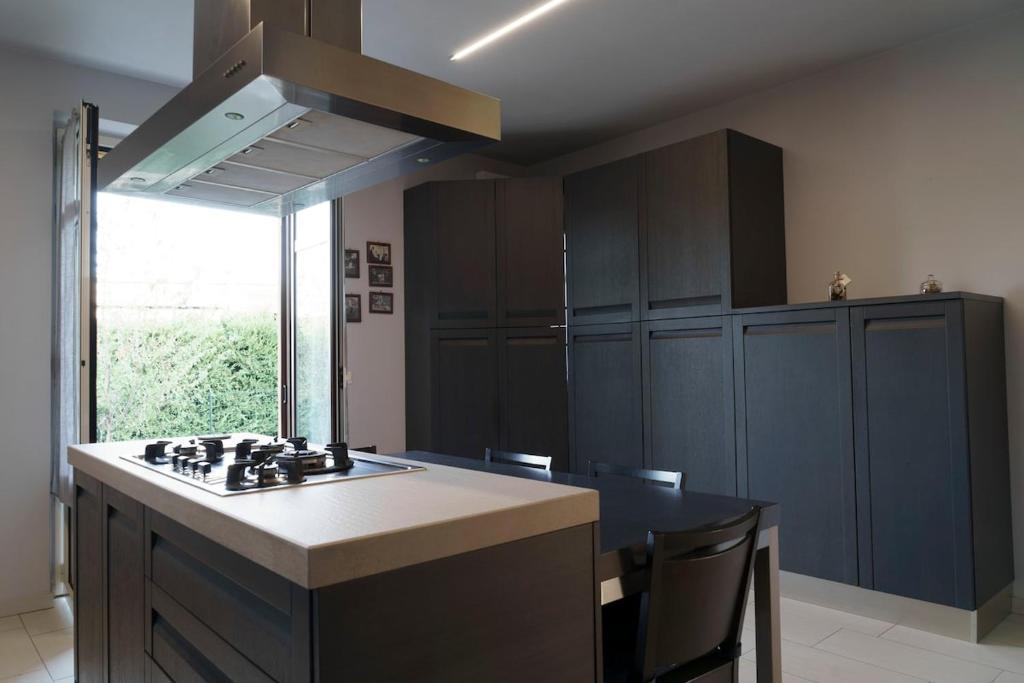 une cuisine avec des armoires noires et un four à plaques de cuisson dans l'établissement Ca du Ji'uu, villa con piscina, à Castellinaldo