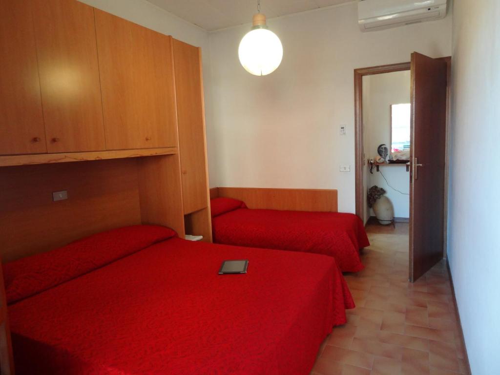 - une chambre avec 2 lits rouges et un miroir dans l'établissement Hotel Residenza Giardino, à Bellaria-Igea Marina