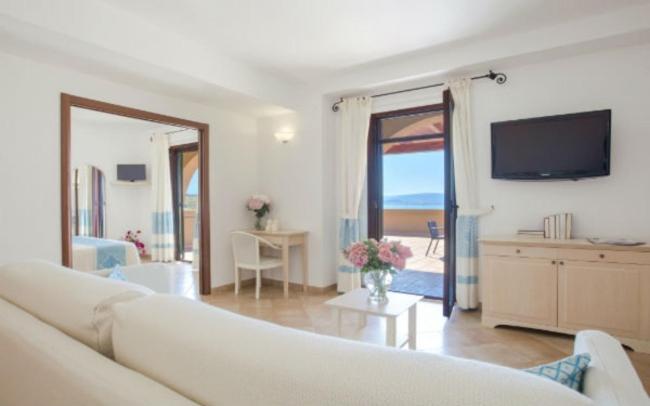 un salon avec un canapé blanc et une télévision dans l'établissement Hotel Dei Pini, à Alghero