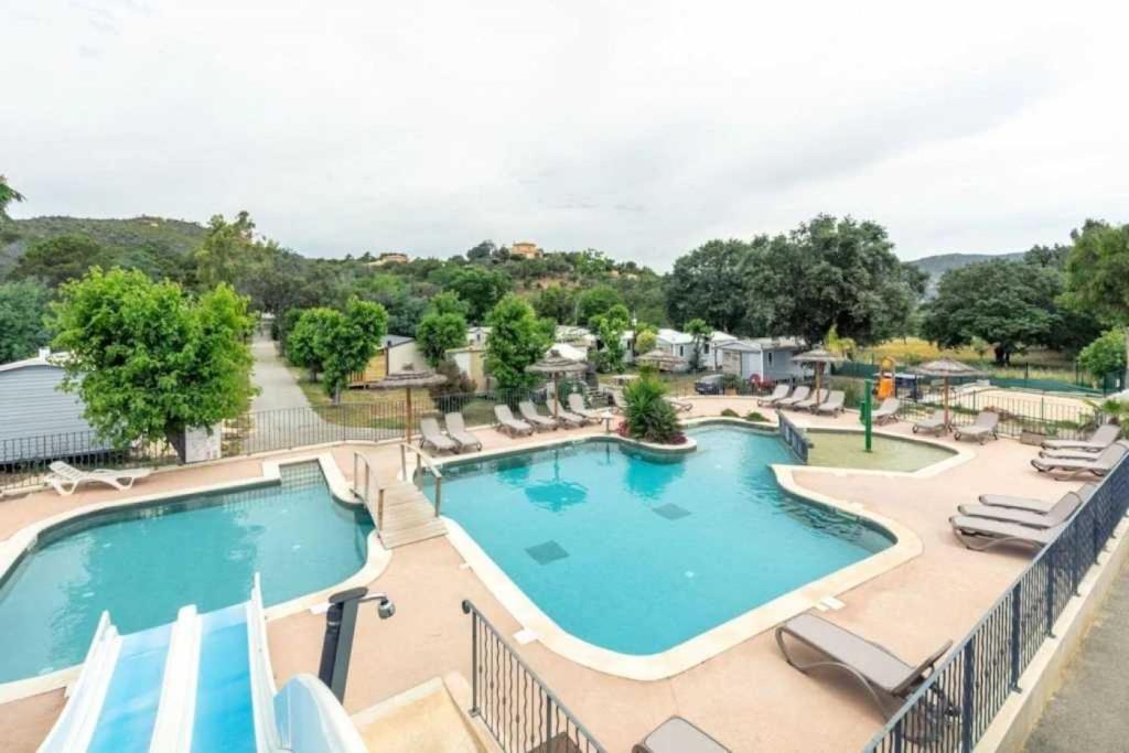 une piscine avec des chaises longues et un complexe hôtelier dans l'établissement Camping 3 étoiles - Piscine - ccaffbe, à Bormes-les-Mimosas