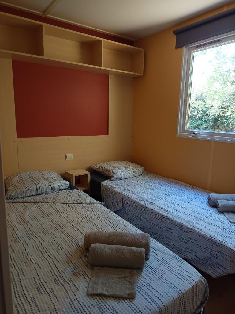 une chambre avec deux lits et une fenêtre dans l'établissement Mobilhome dans camping 3 étoiles en Provence, à La Roque-dʼAnthéron