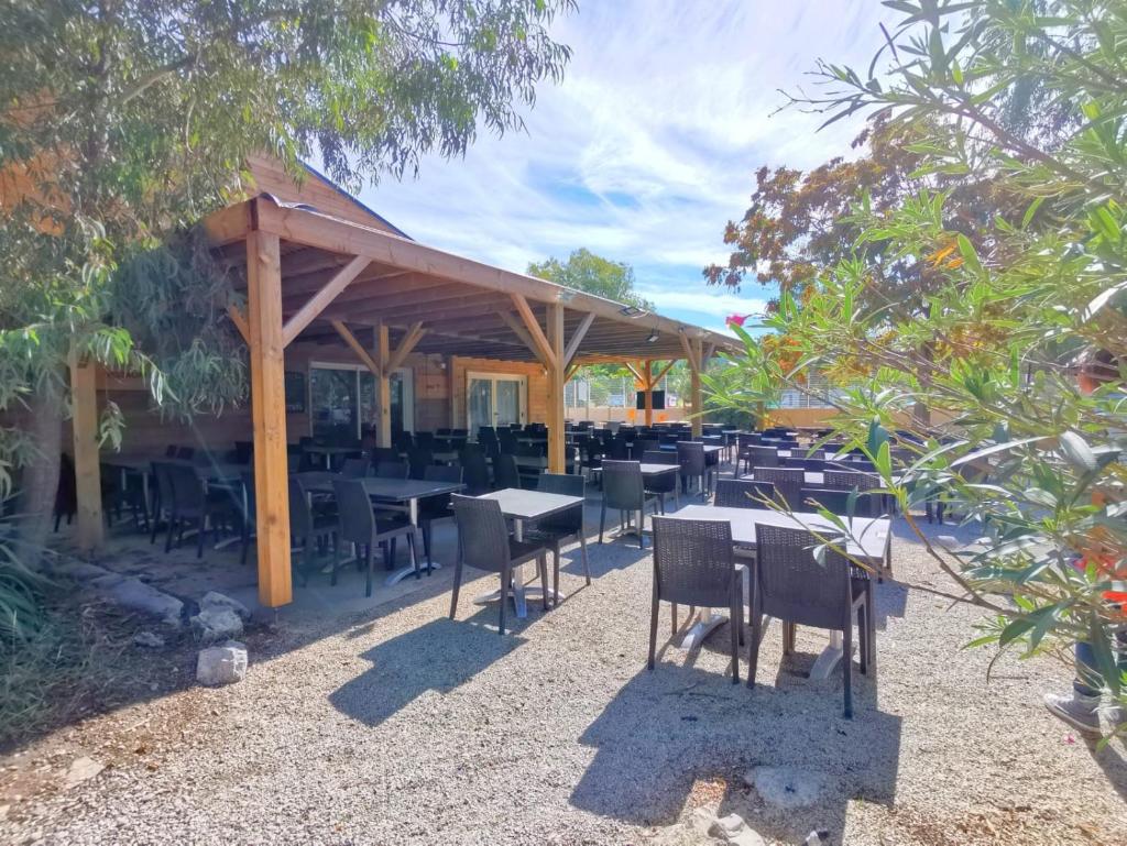 un restaurant avec des tables et des chaises sous un pavillon dans l'établissement Mobilhome dans camping 3 étoiles en Provence, à La Roque-dʼAnthéron