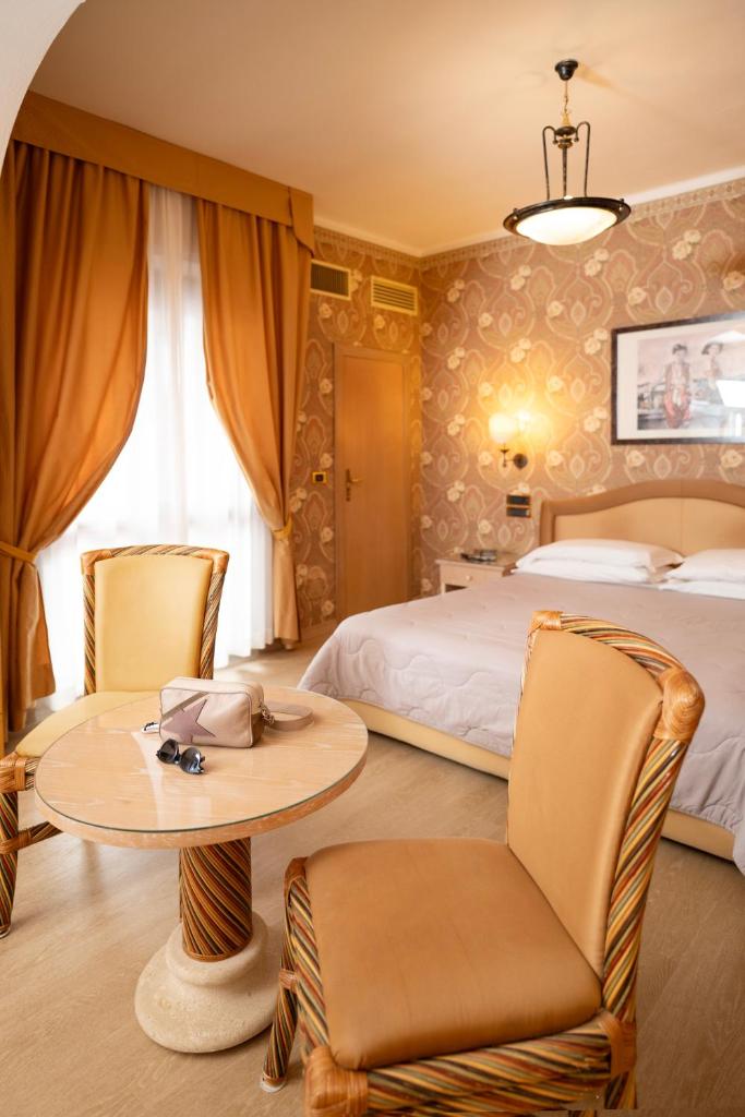 une chambre d'hôtel avec un lit, une table et des chaises dans l'établissement Hotel Promenade, à Montesilvano