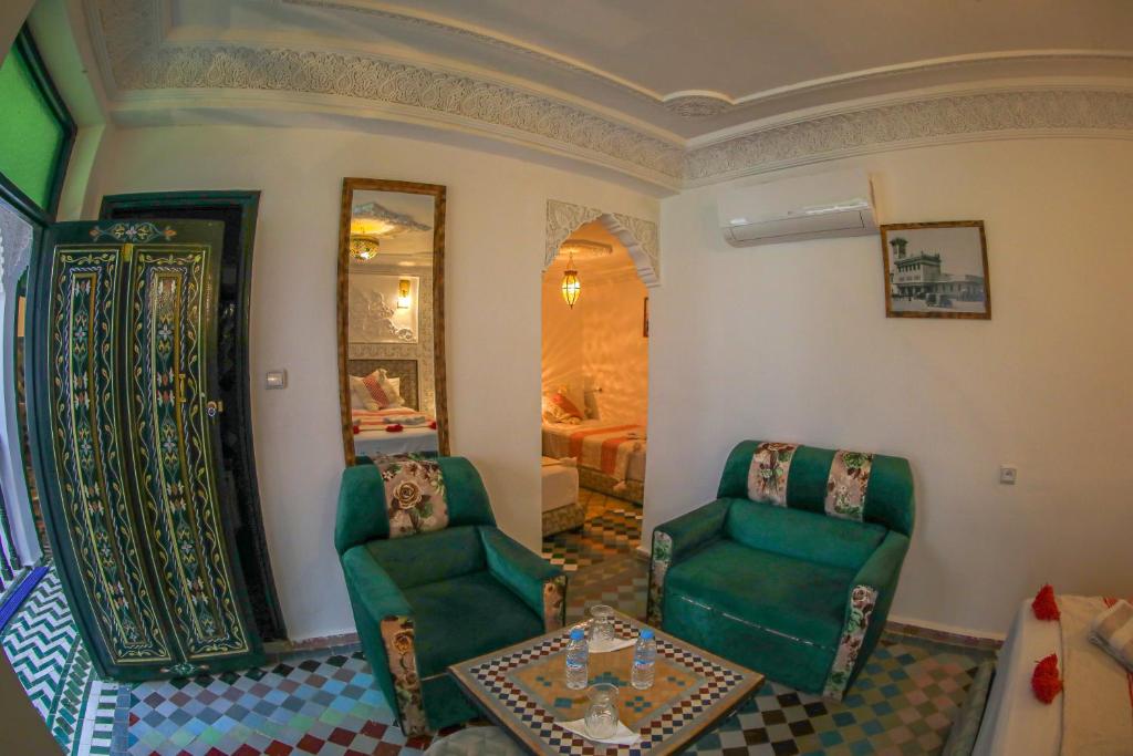 - un salon avec deux chaises vertes et une table dans l'établissement Riad Yamna Fez, à Fès
