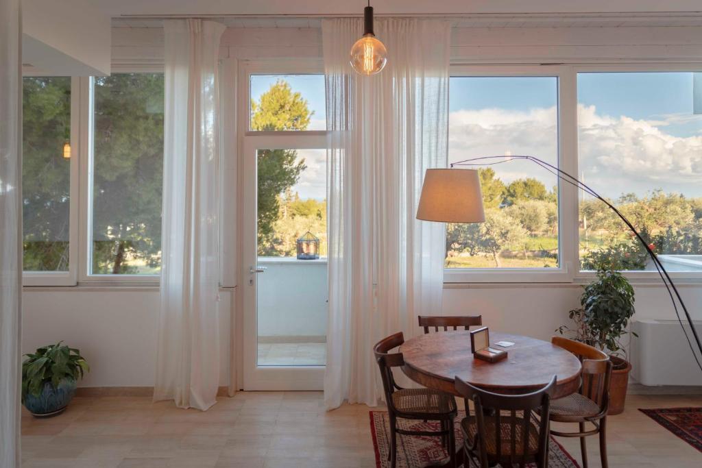 un salon avec une table, des chaises et des fenêtres dans l'établissement Musa Maris - Villa panoramica con piscina, à Conversano