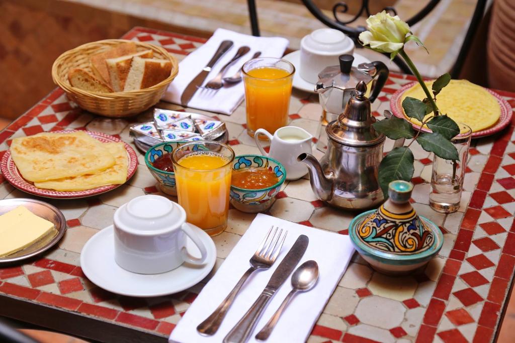 une table avec des assiettes et des ustensiles sur un tissu de table rouge et blanc dans l'établissement Riad Marrakiss, à Marrakech