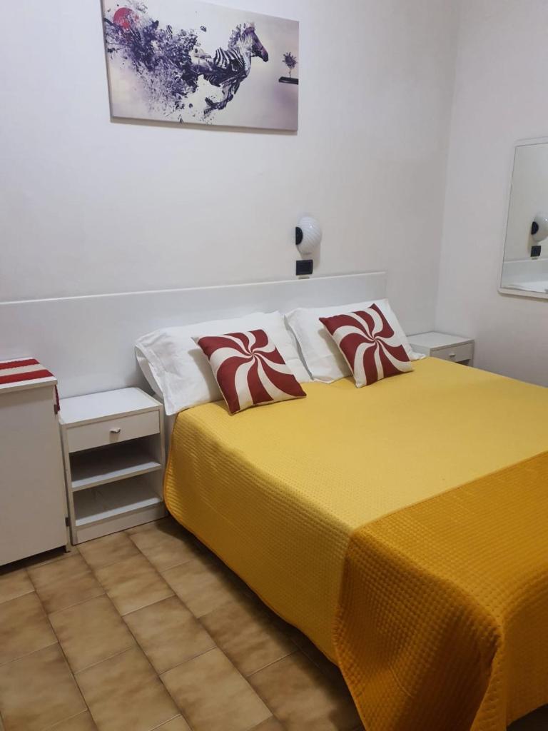 - une chambre dotée d'un lit jaune avec des oreillers rouges et blancs dans l'établissement Hotel Residence Fausta, à Bellaria-Igea Marina