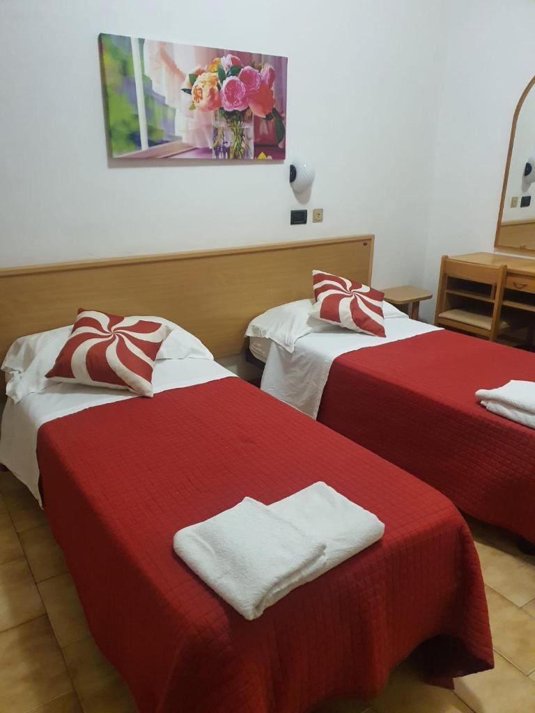 Cette chambre d'hôtel comprend 2 lits avec des draps rouges et blancs. dans l'établissement Hotel Residence Fausta, à Bellaria-Igea Marina