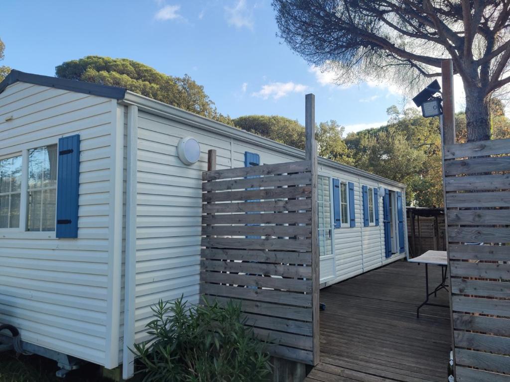 une maison blanche avec une terrasse en bois dans l'établissement Mobilhome résidentiel, à Gassin