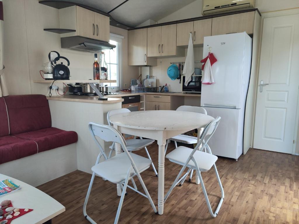 une cuisine avec une table, des chaises et un réfrigérateur dans l'établissement Mobilhome résidentiel, à Gassin