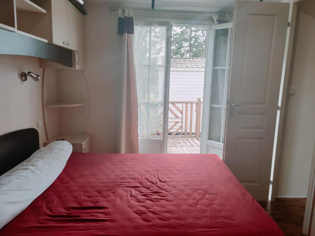 une chambre avec un lit rouge et une porte donnant sur un balcon dans l'établissement Mobilhome résidentiel, à Gassin 32 autres photos