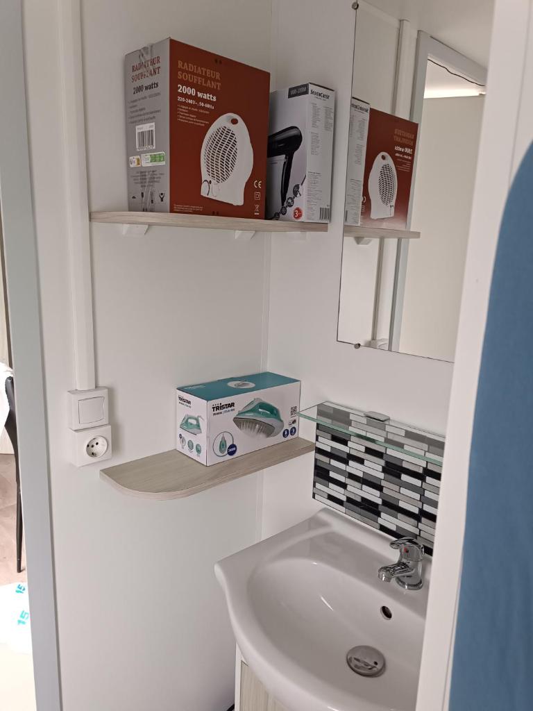 La salle de bains est pourvue d'un lavabo et d'étagères. dans l'établissement Les Ch'tis Normands !, à Litteau