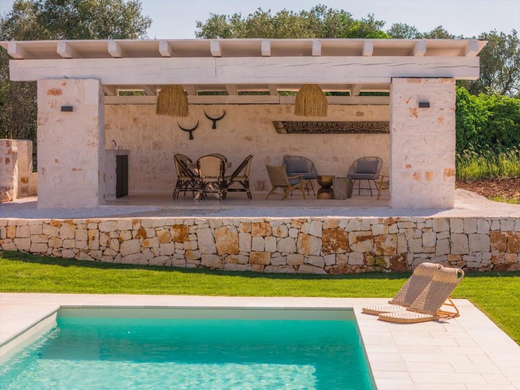 un patio avec une piscine et un mur en pierre dans l'établissement Villa Batu stylish 2 bedroom, à Cisternino