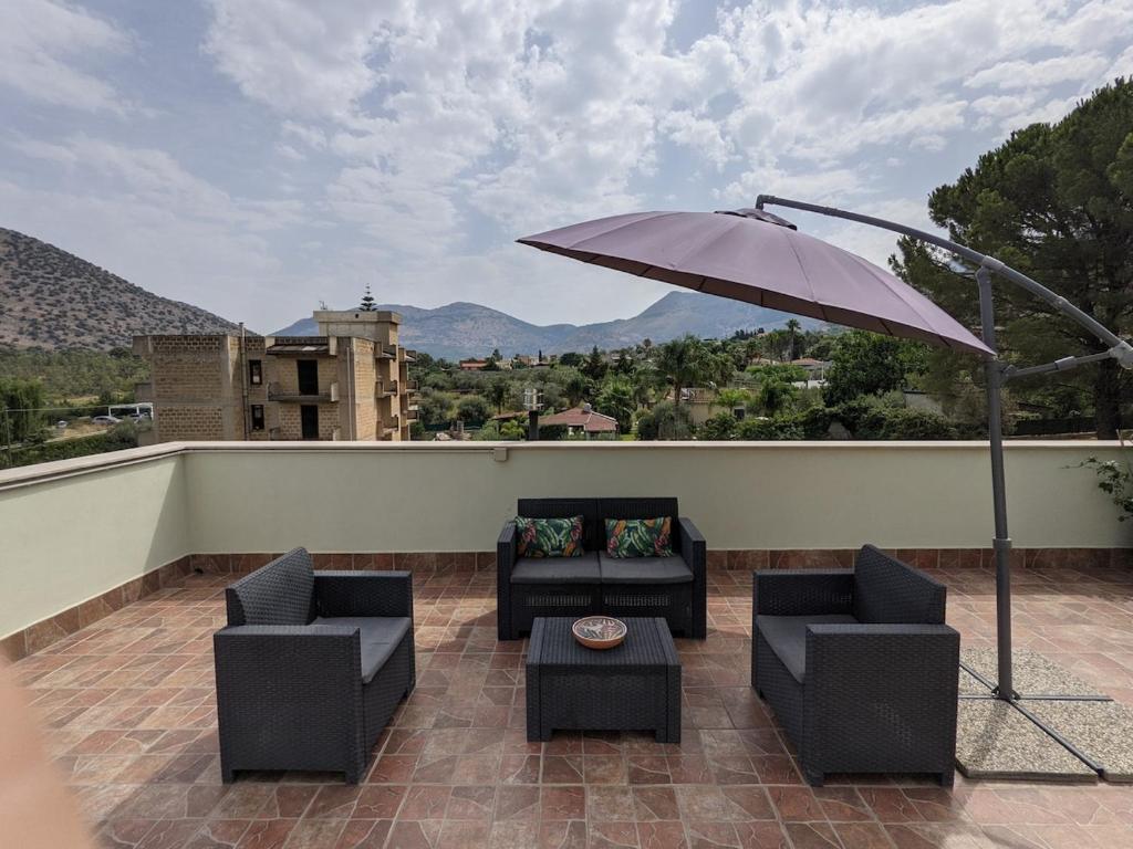 un patio avec deux chaises et un parasol dans l'établissement Villa with private pool and wonderful view, à Carini