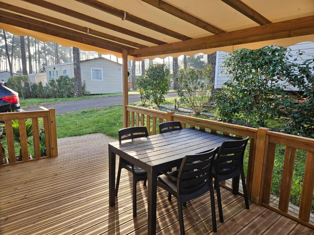 une terrasse en bois avec une table et des chaises dessus dans l'établissement O'ContisParadise, à Saint-Julien-en-Born