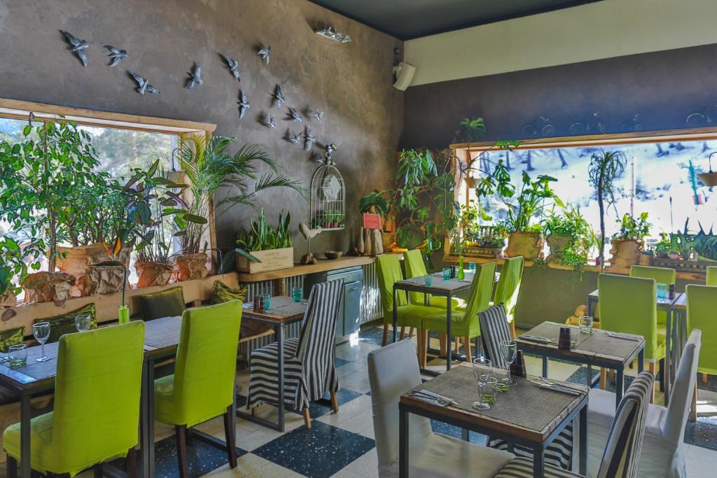 un restaurant avec des tables, des chaises et des oiseaux sur le mur dans l'établissement Hotel Green Ecolodge, à La Colmiane