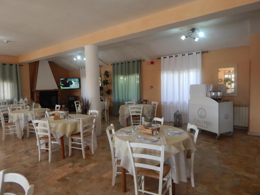 une salle à manger avec des tables et des chaises blanches dans l'établissement Hotel Calypso, à Ardea