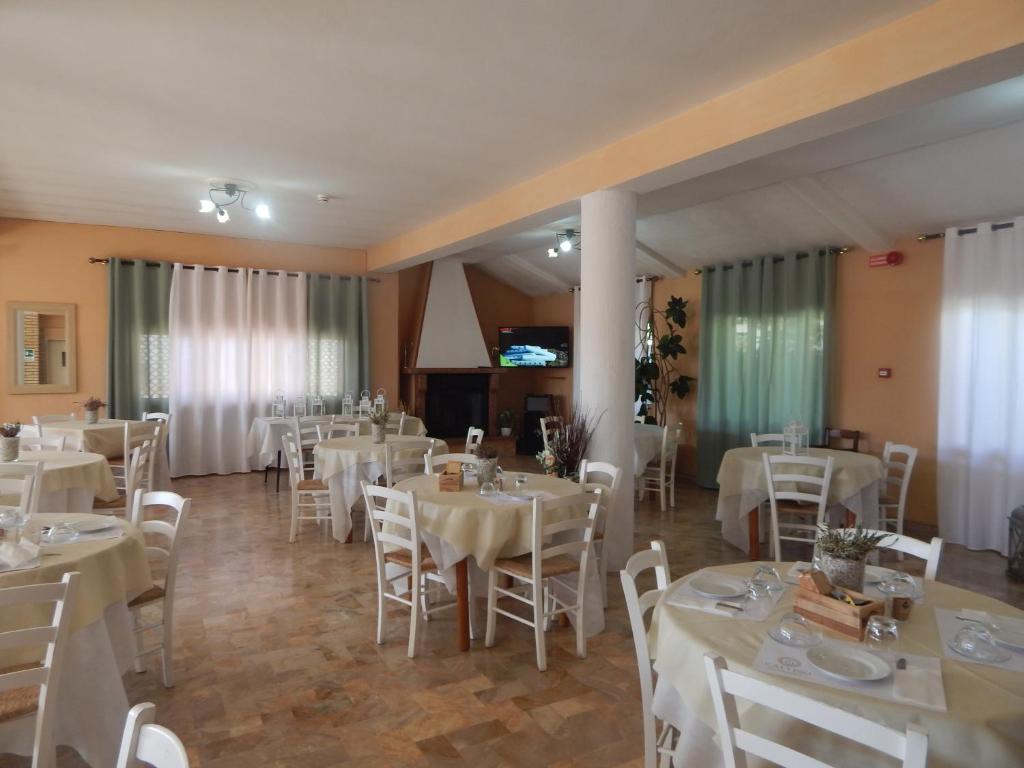 une salle de banquet avec des tables et des chaises blanches dans l'établissement Hotel Calypso, à Ardea 25 autres photos