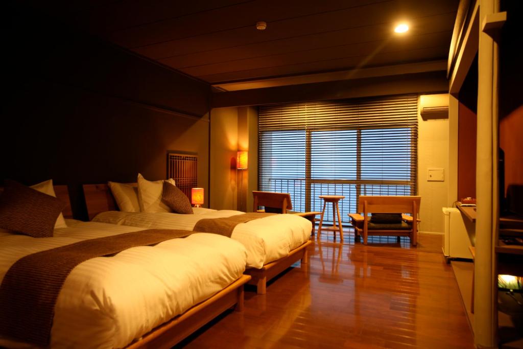 une chambre d'hôtel avec deux lits et une table dans l'établissement Tabinoyado Ushionoakari Geiboso, à Shima