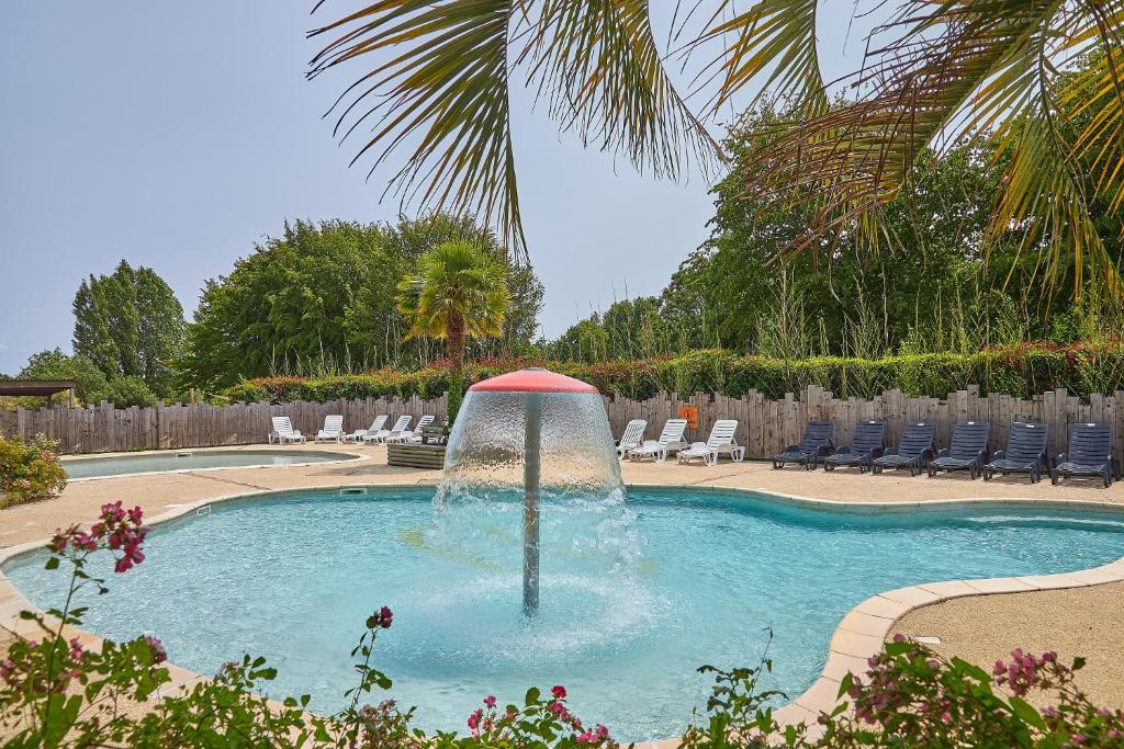 une fontaine dans une piscine avec des chaises longues dans l'établissement Camping Domaine de Kermario, à Carnac 28 autres photos