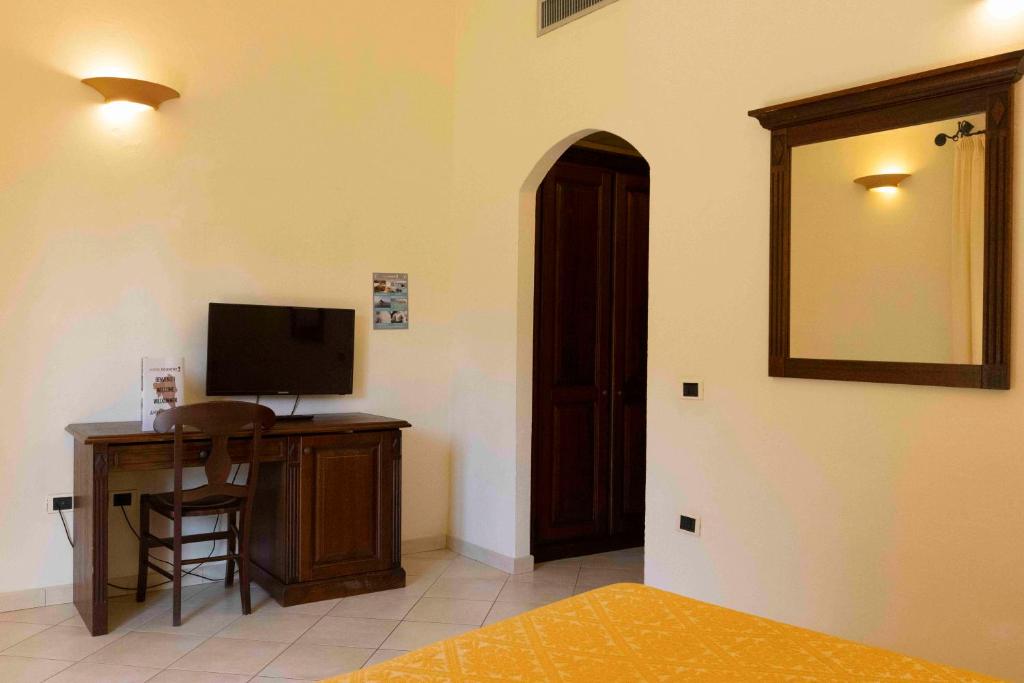 Cette chambre comprend un bureau avec une télévision et un miroir. dans l'établissement Horse Country Resort Congress & Spa - Hotel Medar, à Arborea