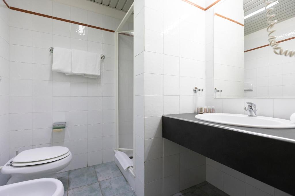 une salle de bain blanche avec toilettes et lavabo dans l'établissement Horse Country Resort Congress & Spa - Hotel Castello, à Arborea