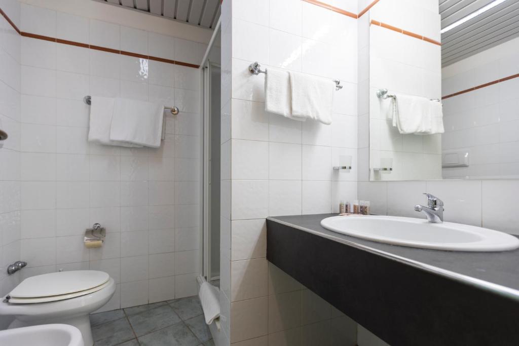 une salle de bain blanche avec un lavabo et des toilettes dans l'établissement Horse Country Resort Congress & Spa - Hotel Castello, à Arborea