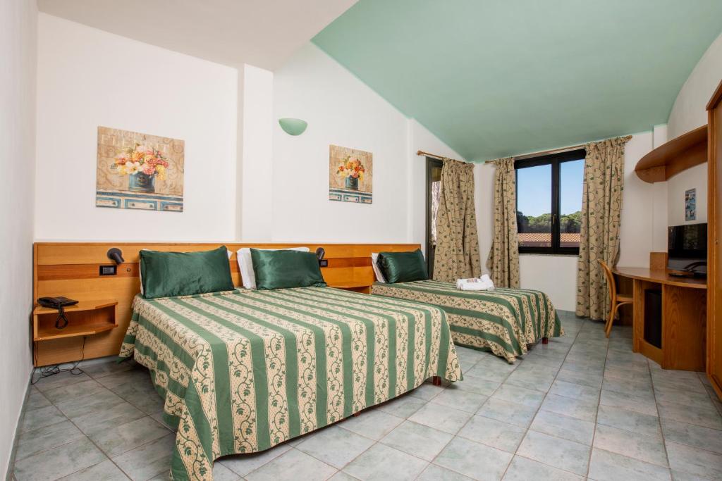 une chambre d'hôtel avec deux lits et un bureau dans l'établissement Horse Country Resort Congress & Spa - Hotel Castello, à Arborea