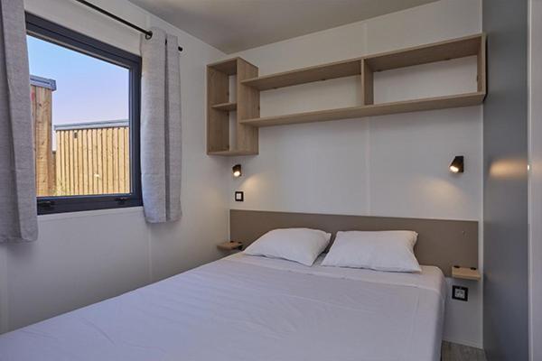 une chambre avec un lit blanc et une fenêtre dans l'établissement Camping Les Gorges de Provence, à Saint-Laurent-du-Verdon