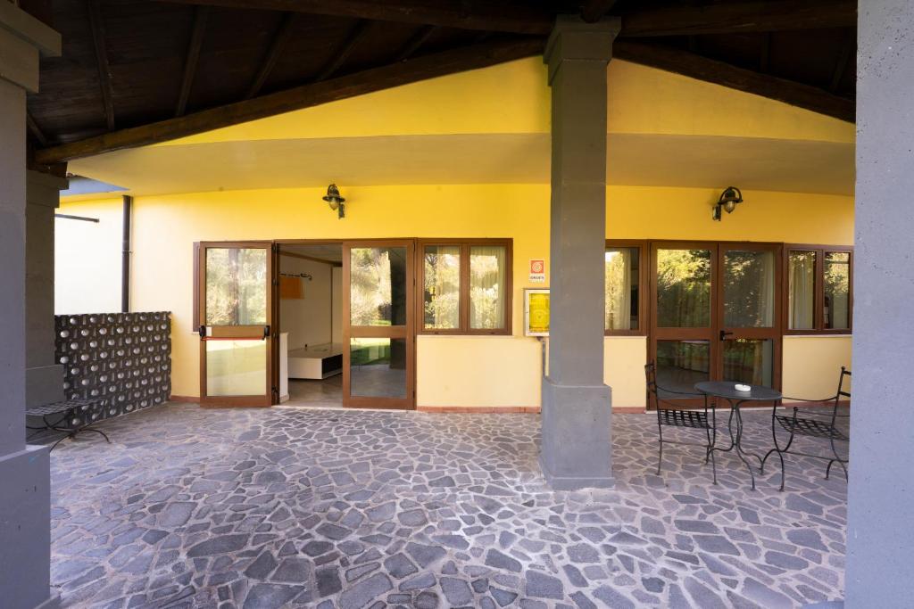un grand bâtiment jaune avec une table et des chaises à l'intérieur dans l'établissement Horse Country Resort Congress & Spa - Hotel Ribot, à Arborea