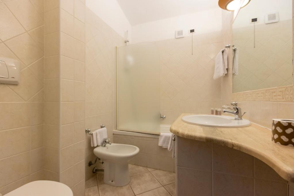 une salle de bain avec un lavabo, des toilettes et un miroir dans l'établissement Horse Country Resort Congress & Spa - Hotel Ribot, à Arborea