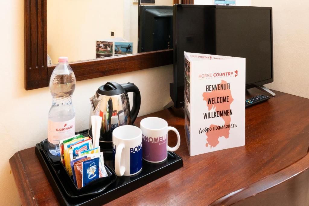 un bureau avec des tasses, un livre et une bouteille d'eau dans l'établissement Horse Country Resort Congress & Spa - Hotel Ribot, à Arborea