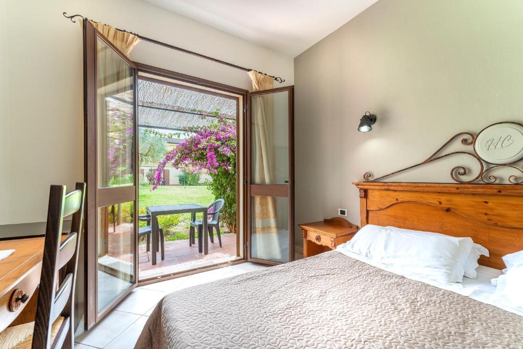 une chambre avec un lit et un balcon avec une table dans l'établissement Horse Country Resort Congress & Spa - Hotel Ribot, à Arborea