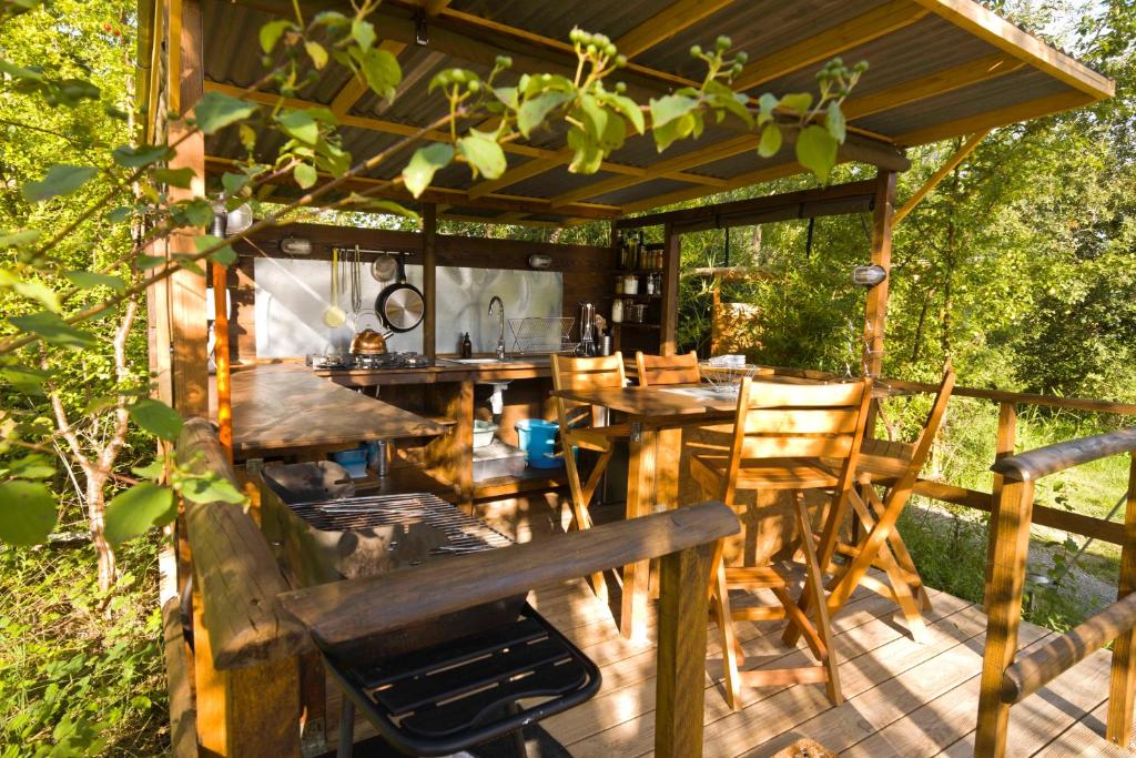 une terrasse en bois avec une table et des chaises dans l'établissement Le Camp, à Varen 17 autres photos