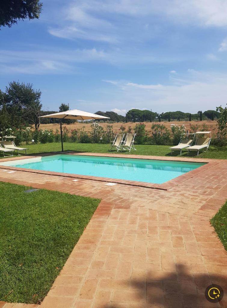 - une piscine avec 2 chaises longues et un parasol dans l'établissement Tenuta la Valle Relaxing Oasis with pool in Tuascany, à Vada