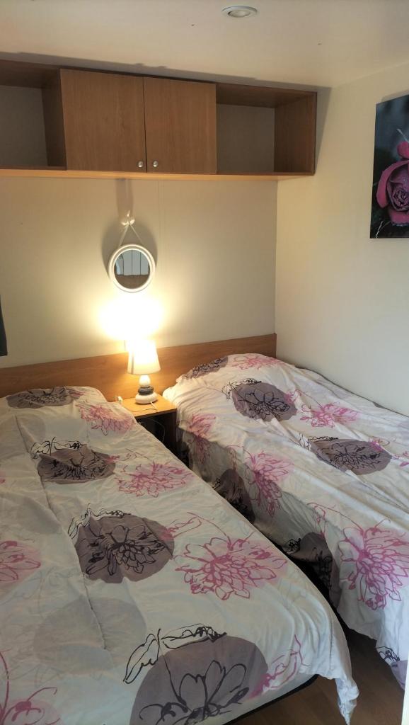 - une chambre avec 2 lits avec des fleurs roses dans l'établissement Mobile Home à Louannec, à Louannec