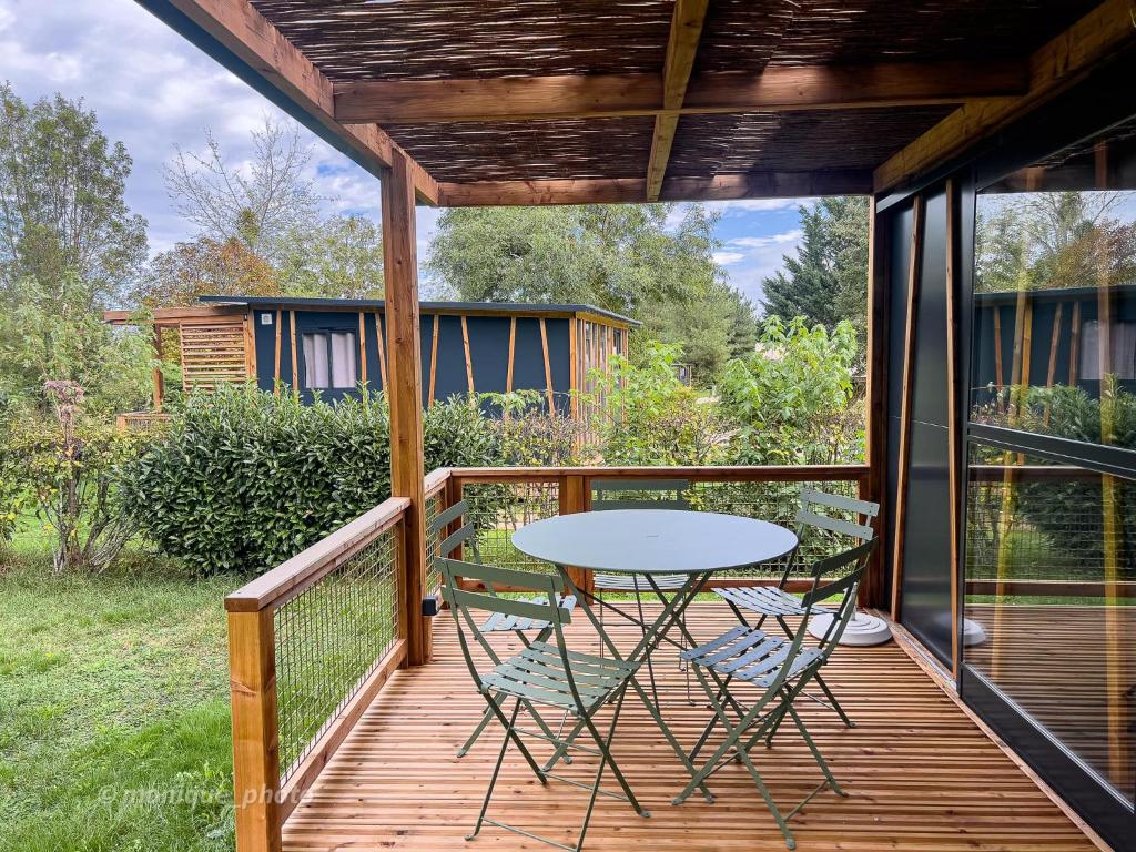 un patio avec une table et des chaises sur une terrasse dans l'établissement Camping Onlycamp le Champ d'été, à Reyssouze