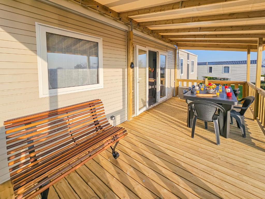 une terrasse en bois avec un banc et une table. dans l'établissement La Sérénité Normande, à Litteau