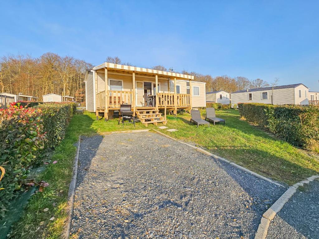une maison construite avec une terrasse couverte et une allée. dans l'établissement La Sérénité Normande, à Litteau
