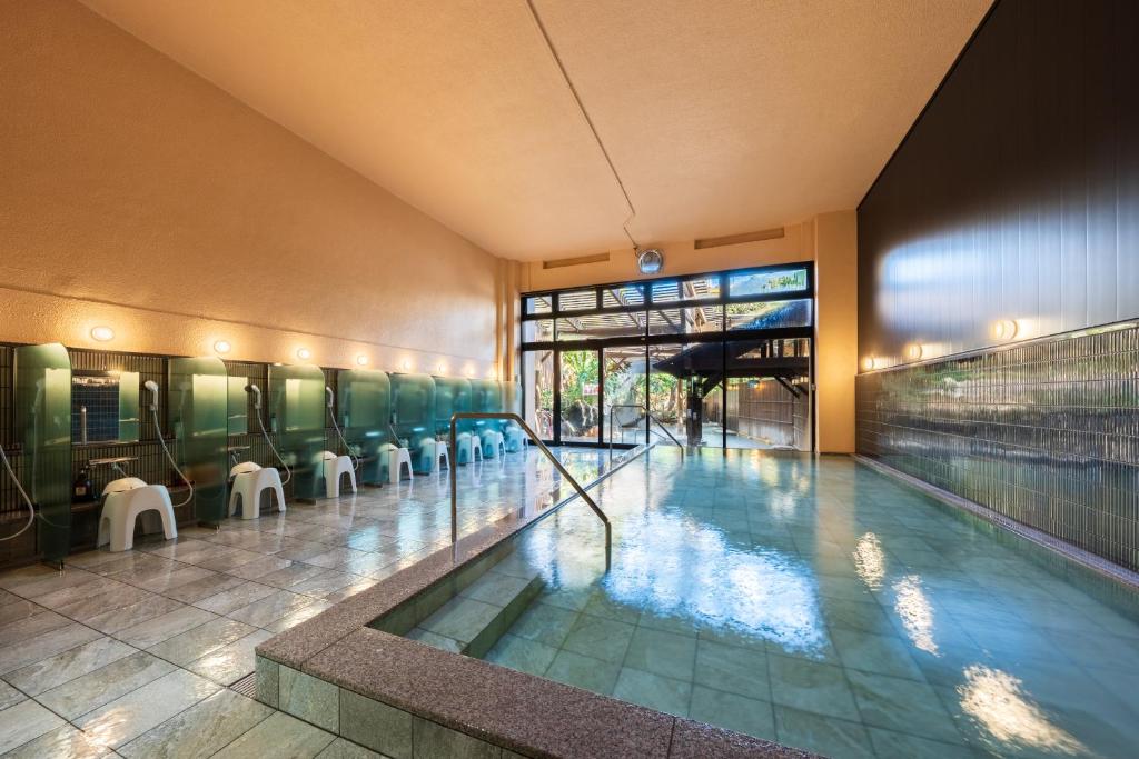 - une piscine dans un bâtiment avec des tables et des chaises dans l'établissement Beppu Kannawa Onsen Oniyama Hotel, à Beppu