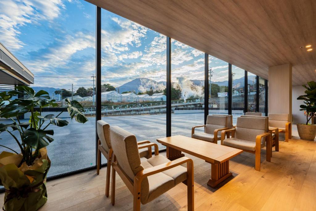 une pièce avec une table et des chaises et une grande fenêtre dans l'établissement Beppu Kannawa Onsen Oniyama Hotel, à Beppu